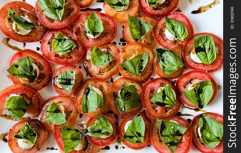 Tomatoes basil craker and balsamic vinegar on a white plate. Tomatoes basil craker and balsamic vinegar on a white plate