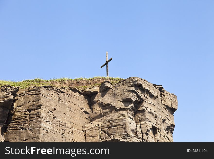 The cross on the rock over the sea meets floating ships