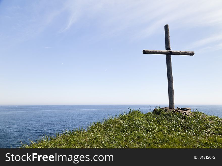The cross on the rock over the sea meets floating ships