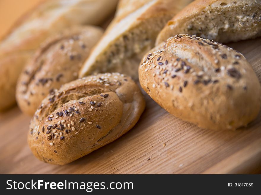 Rolls with sesame seeds over wooden cutting board background. Selective focus. Rolls with sesame seeds over wooden cutting board background. Selective focus.