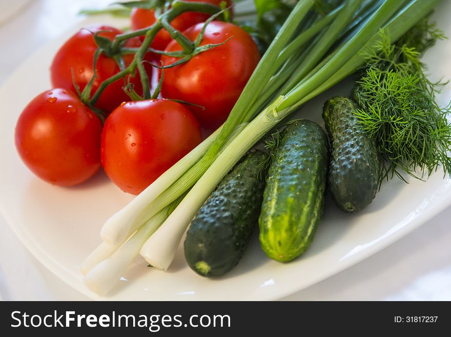 Fresh and tasty vegetables: tomatoes, cucumbers, green dill, and spring onions. Blurred background. Selective focus. Fresh and tasty vegetables: tomatoes, cucumbers, green dill, and spring onions. Blurred background. Selective focus.