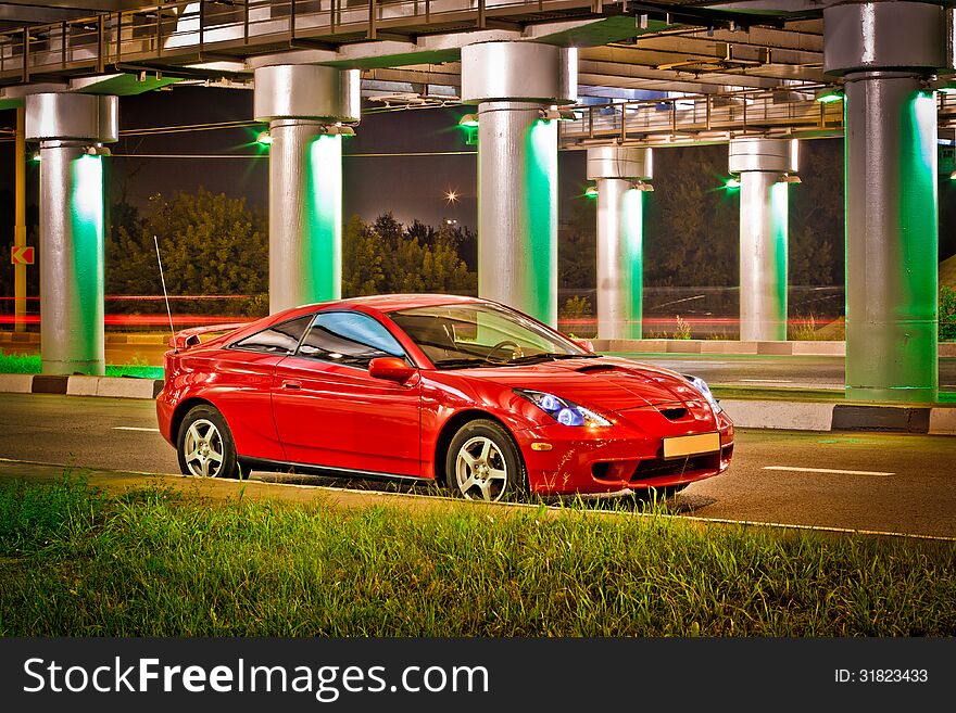 Red sport car under the brige with lights.