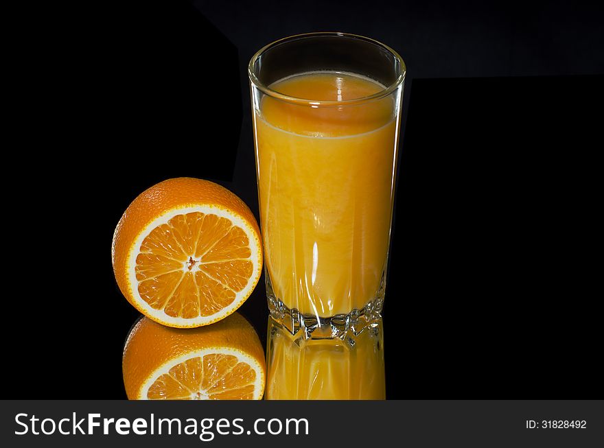 Fresh orange juice and orange on a black background large. Fresh orange juice and orange on a black background large