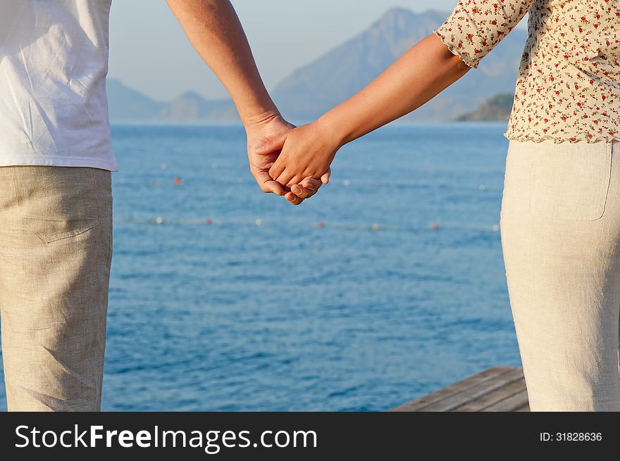 Loving couple holding hands on the background of the sea