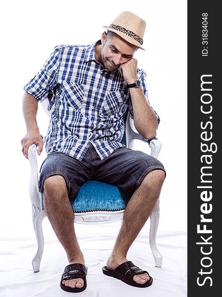 Bored tourist in hat and blue shirt, sitting in a chair and waiting for something. Isolated on white background. Bored tourist in hat and blue shirt, sitting in a chair and waiting for something. Isolated on white background.