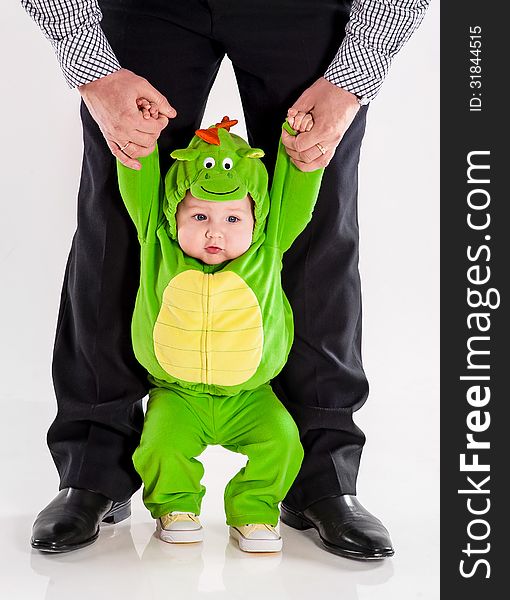 The small son in a green suit of a dragon holds the father by hands. The small son in a green suit of a dragon holds the father by hands