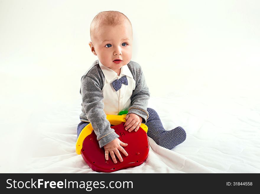 The small child plays with a red toy on a light background. The small child plays with a red toy on a light background
