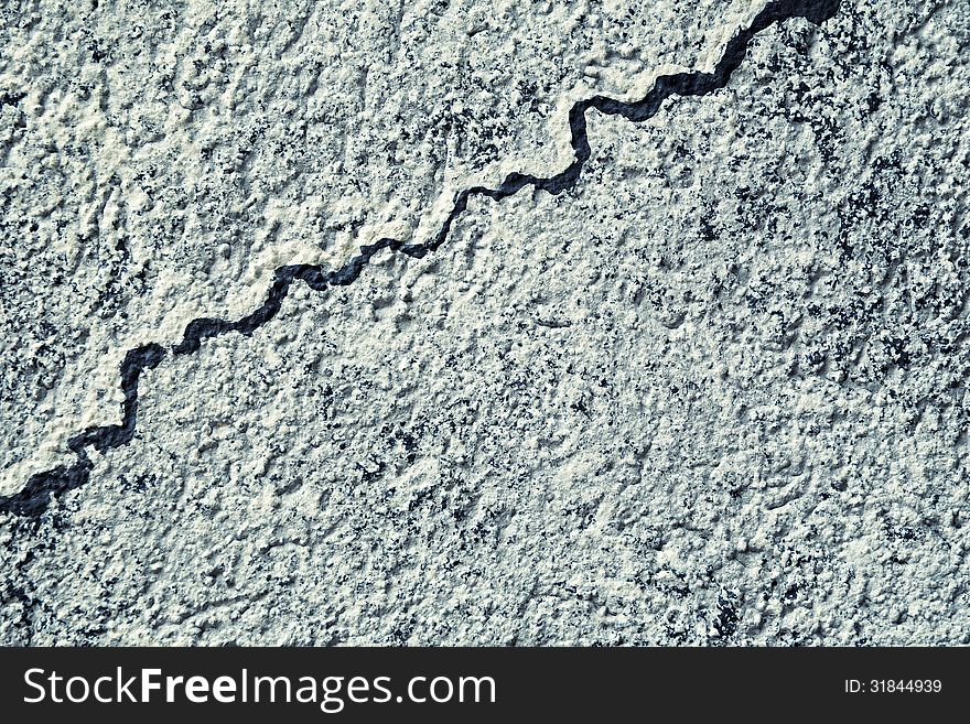 Abstract background of a stone texture detail with a squiggly crack running diagonally through it. Abstract background of a stone texture detail with a squiggly crack running diagonally through it