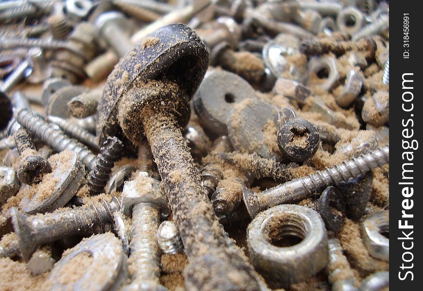 A pile of old bolts and nuts at the bottom of a box in the garage.