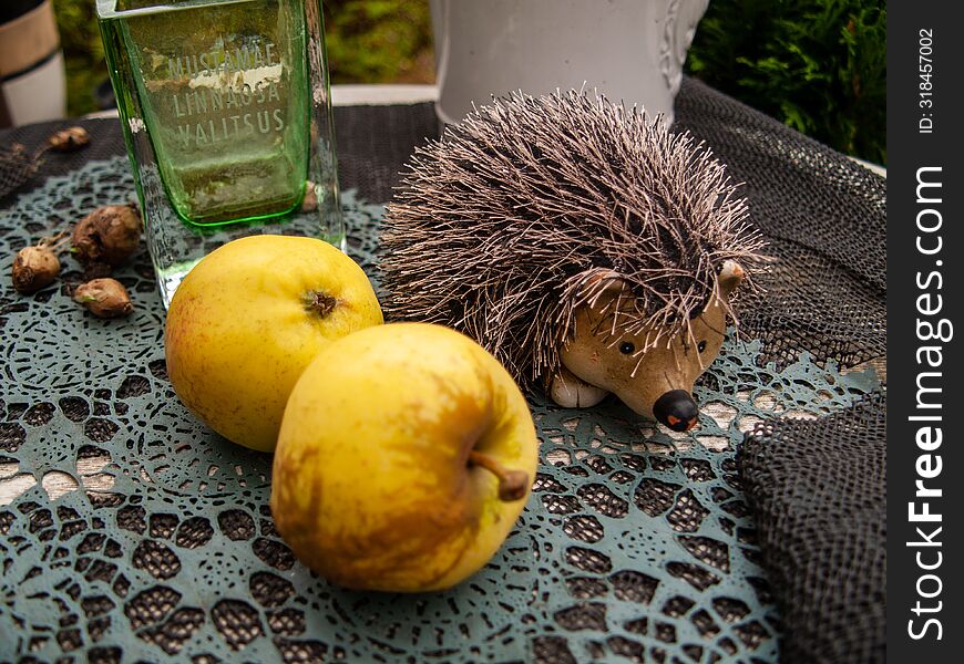 Still life with a toy hedgehog and apples.