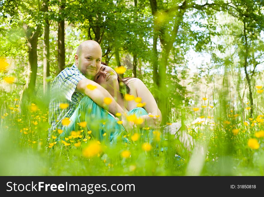 Happy young couple is sitting in a field of buttercups. Happy young couple is sitting in a field of buttercups