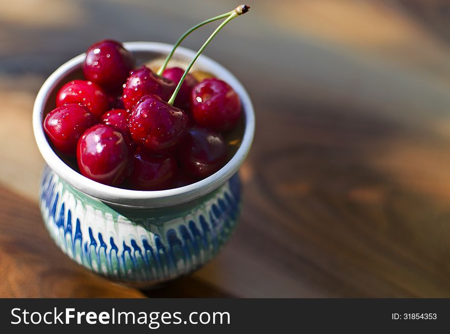 Ripe cherries in a rustic recipient on a wooden surface. Ripe cherries in a rustic recipient on a wooden surface.