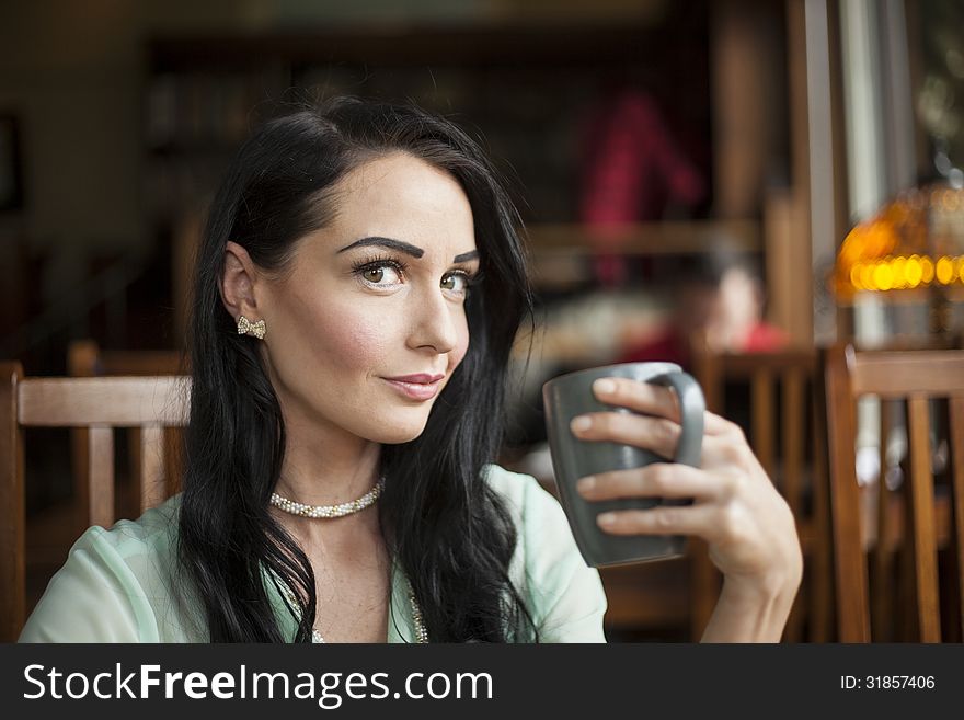 Beautiful young woman with dark brown hair and eyes holding a gray coffee cup. Beautiful young woman with dark brown hair and eyes holding a gray coffee cup.
