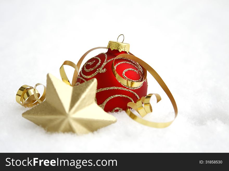 Red-golden bauble with the ribbon on the snow. Red-golden bauble with the ribbon on the snow