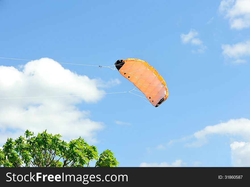 Kite flying on background of blue sky with clouds.