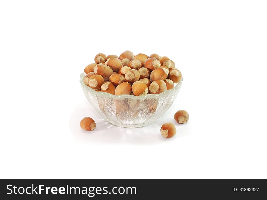 A small glass vase filled with hazelnuts. A small glass vase filled with hazelnuts