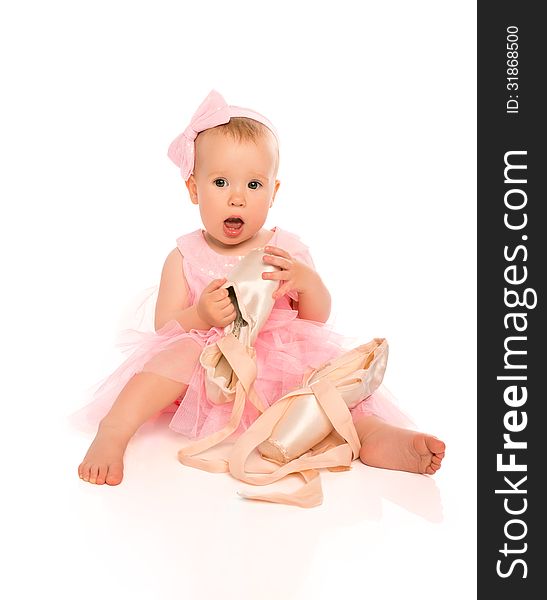 Little baby girl in a pink ballerina dress with pointe shoes isolated on a white background