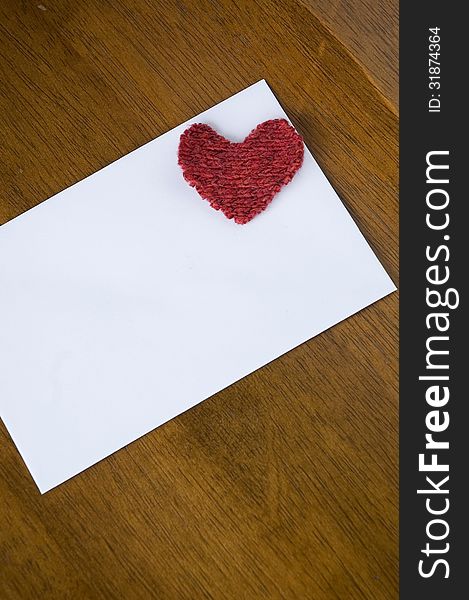White card with red heart on wooden table