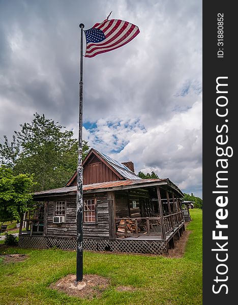 Old log cabin and american flag flying over on a pole