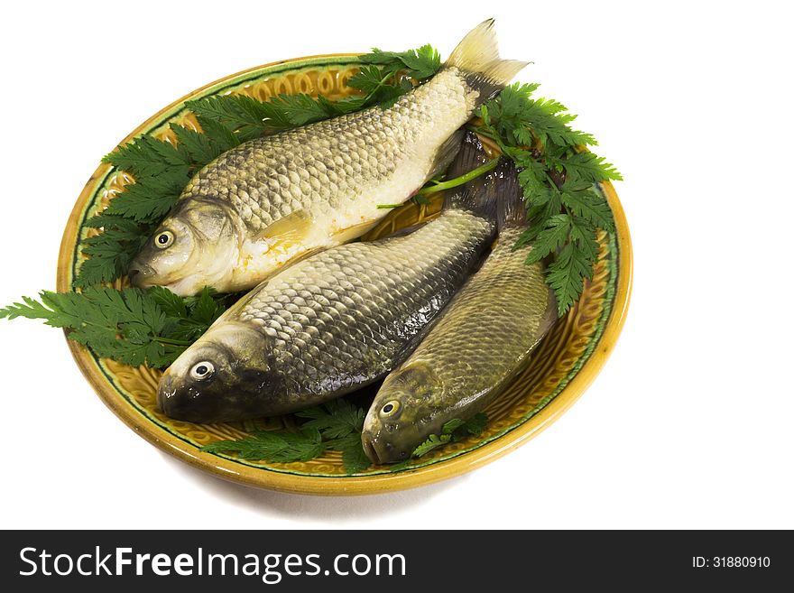 Fresh water fish - carp. Located on ceramic brown the dish with lemon and greens. Fresh water fish - carp. Located on ceramic brown the dish with lemon and greens