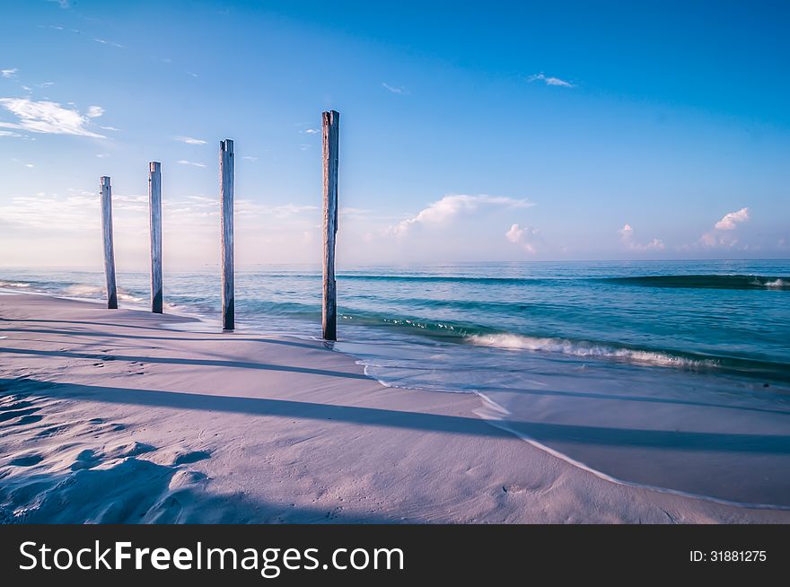 Old pier pile support columns standing along the beach