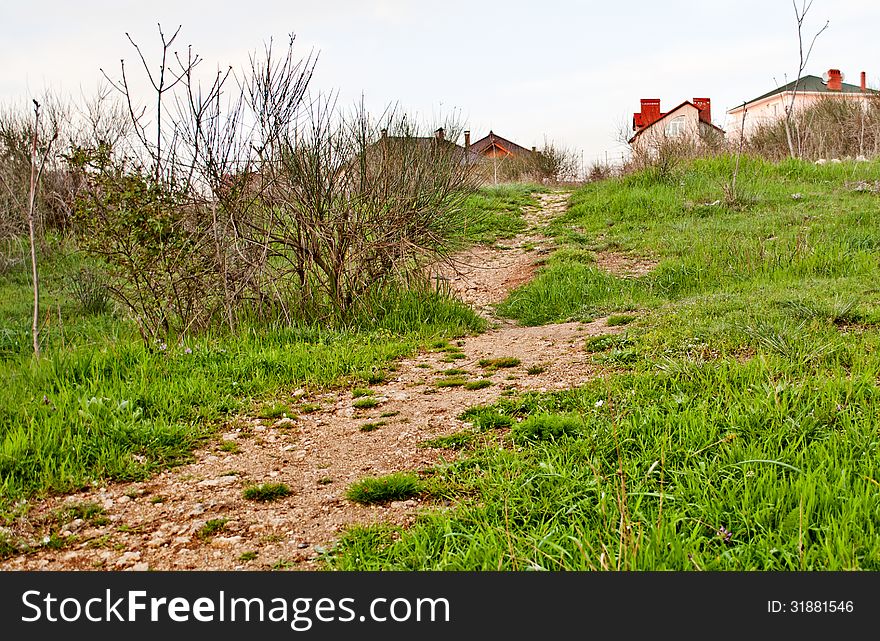 A path in grass going upslope to houses. A path in grass going upslope to houses