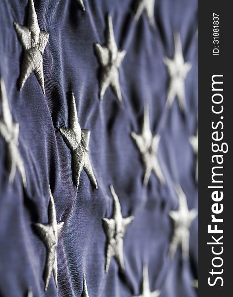 Horizontal close up Shot of American flag focused on the white stars in blue field side lit with shadows. Horizontal close up Shot of American flag focused on the white stars in blue field side lit with shadows