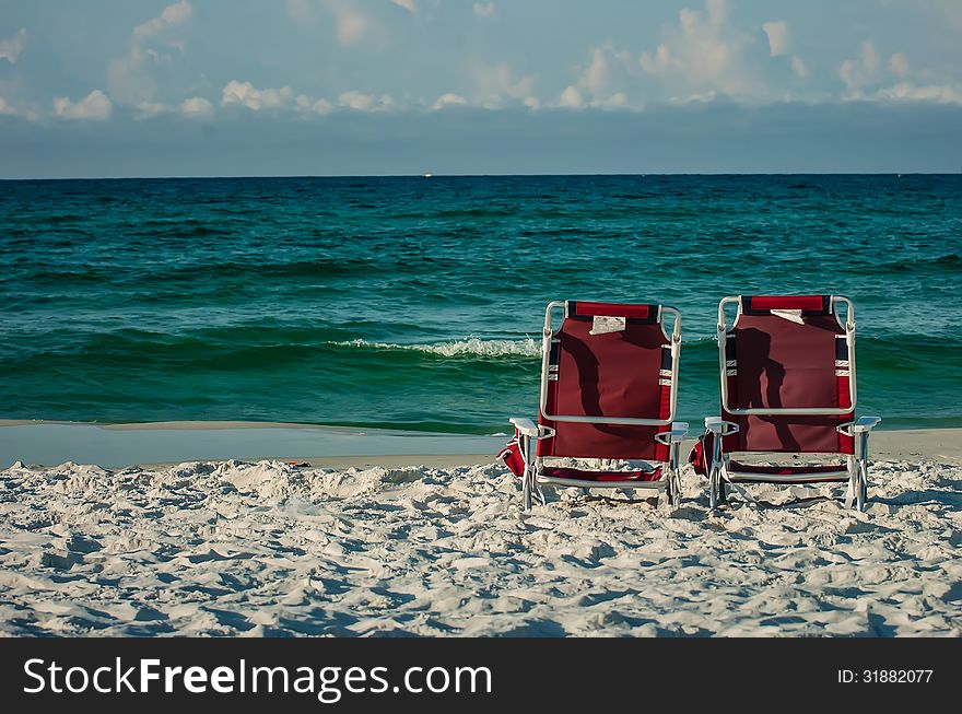 Two chairs on a beach with gulf of mexico background