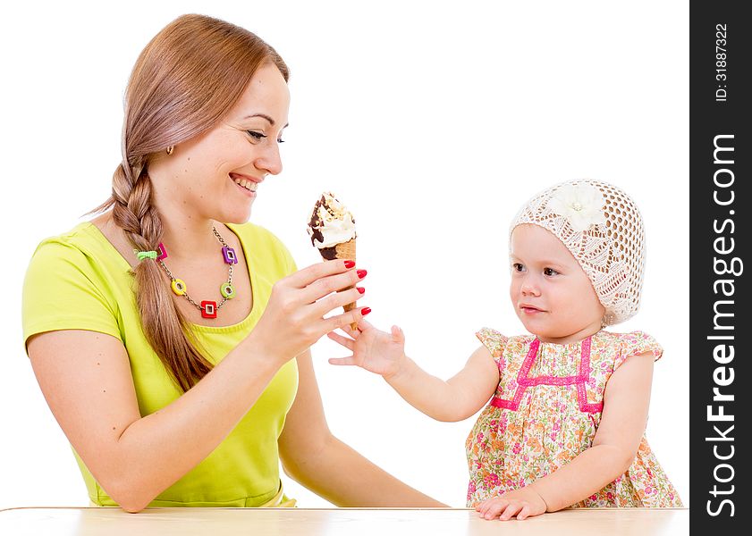Mother giving ice cream to little girl sitting at table