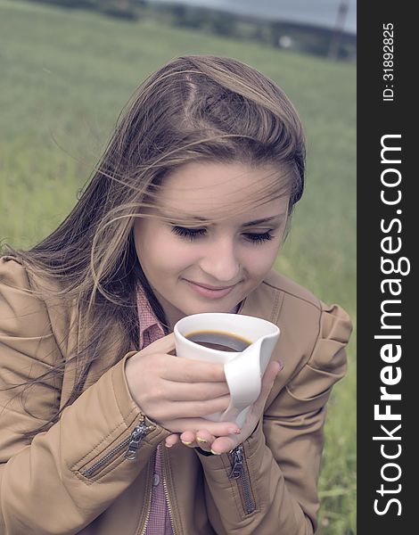 Girl drinks coffee with pleasure outdoors