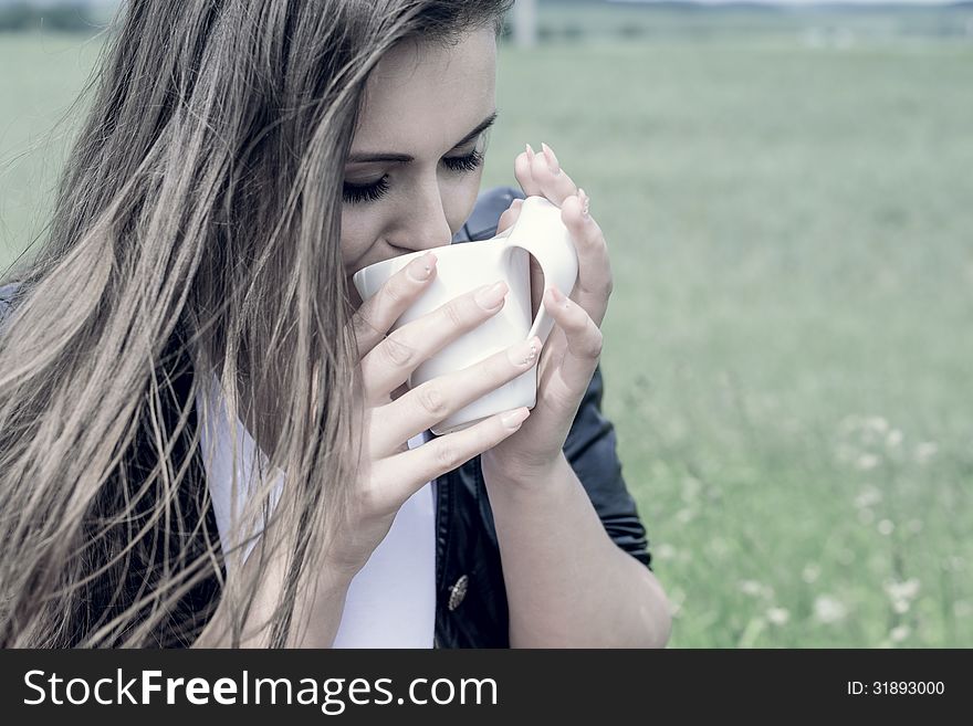 Girl drinks coffee with pleasure outdoors