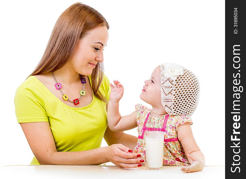 Mother giving milk glass to little girl sitting at table isolated on white