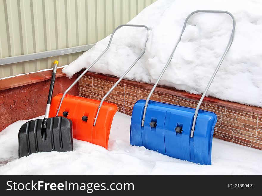 Three snow shovels are on a snow pile in winter