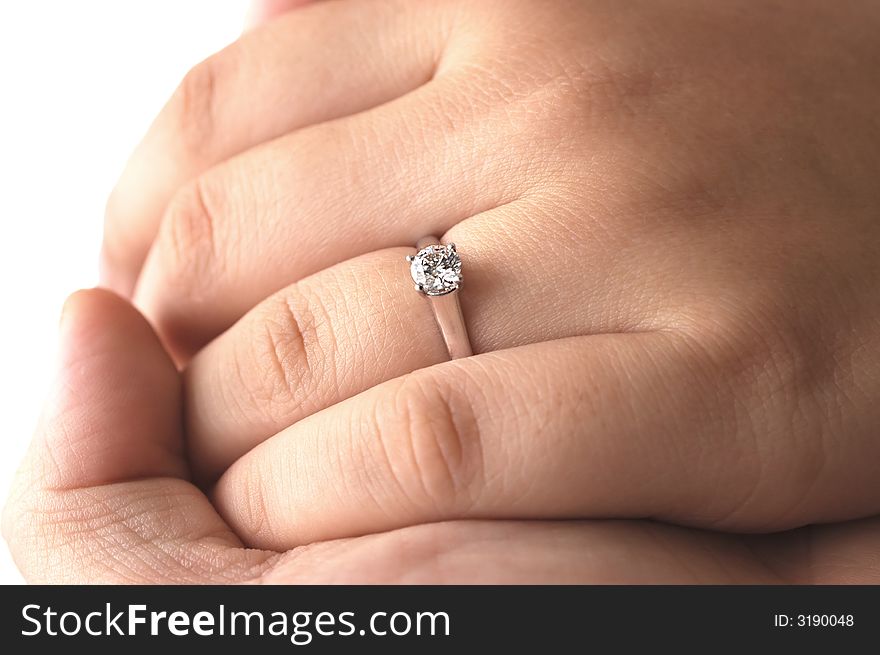 A man holding his fiance's hand with an engagement ring on. A man holding his fiance's hand with an engagement ring on