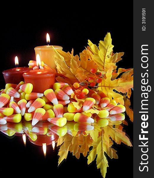 Candles, corn candy, and colorful foliage reflecting on a mirror. Candles, corn candy, and colorful foliage reflecting on a mirror.