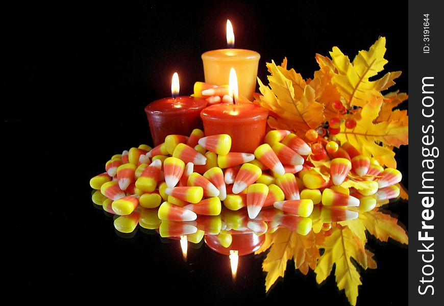 Candles, candy and colorful leaves reflected pn a mirror. Candles, candy and colorful leaves reflected pn a mirror