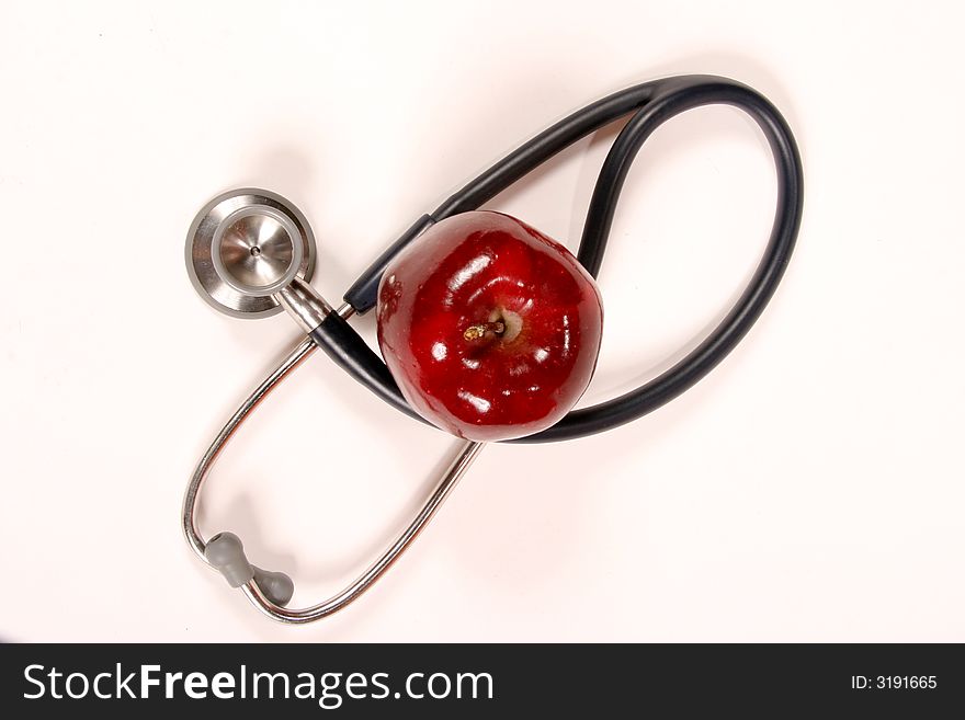 Stethoscope wrapped around an apple on a white background