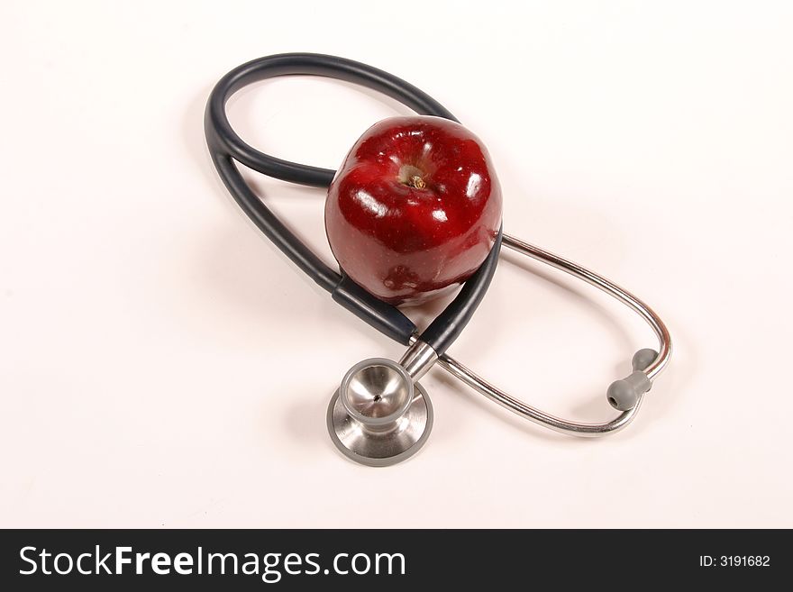 Stethoscope wrapped around an apple on a white background