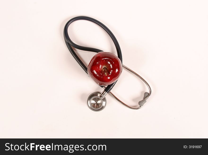 Stethoscope wrapped around an apple on a white background