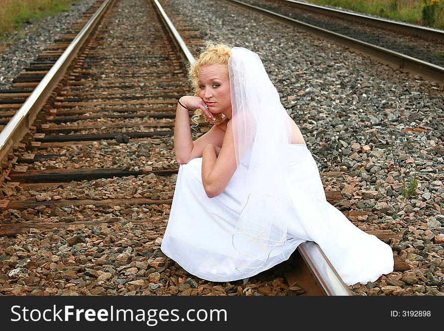 Beautiful bride sitting on the railroad tracks. Beautiful bride sitting on the railroad tracks.