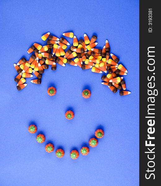 A smily face made with candy, with candy corn hair taken on a blue background. A smily face made with candy, with candy corn hair taken on a blue background.