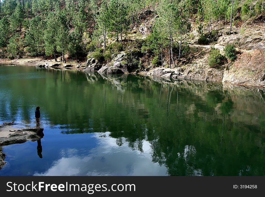 Calm and peaceful waters of a lake with silhouette of a person contemplating nature. Calm and peaceful waters of a lake with silhouette of a person contemplating nature