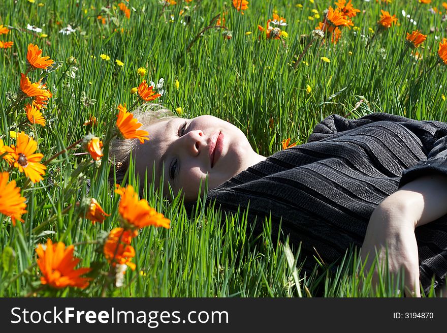 Blonde woman in casual clothes lying in a field of flowers. Blonde woman in casual clothes lying in a field of flowers