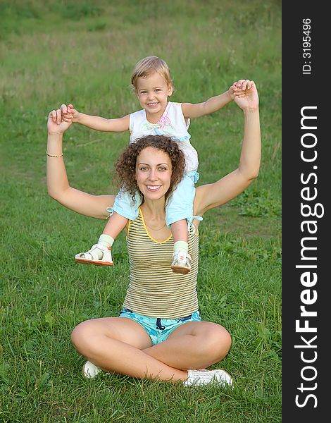 Daughter sits on the shoulders in mother on to the meadow. Daughter sits on the shoulders in mother on to the meadow