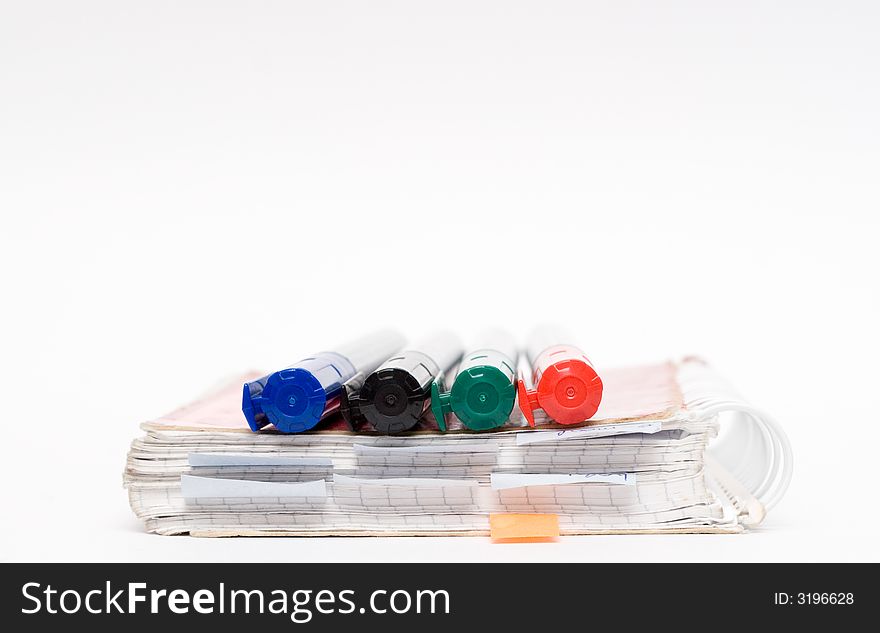 Three highlighters and notebook isolated on grey. Three highlighters and notebook isolated on grey