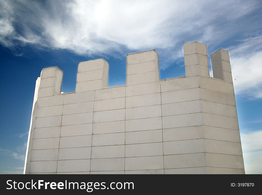 White castle tower in front of blue sky and clouds