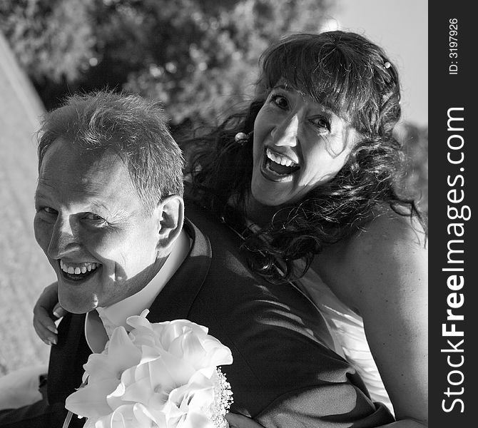 Happy and laughing bridal couple. He carries her. Diagonal view, square format, monochrome. They are beaming for joy!. Happy and laughing bridal couple. He carries her. Diagonal view, square format, monochrome. They are beaming for joy!