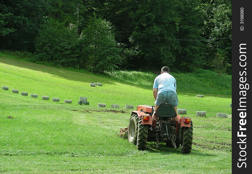 Men with tractor work in the green grass park field