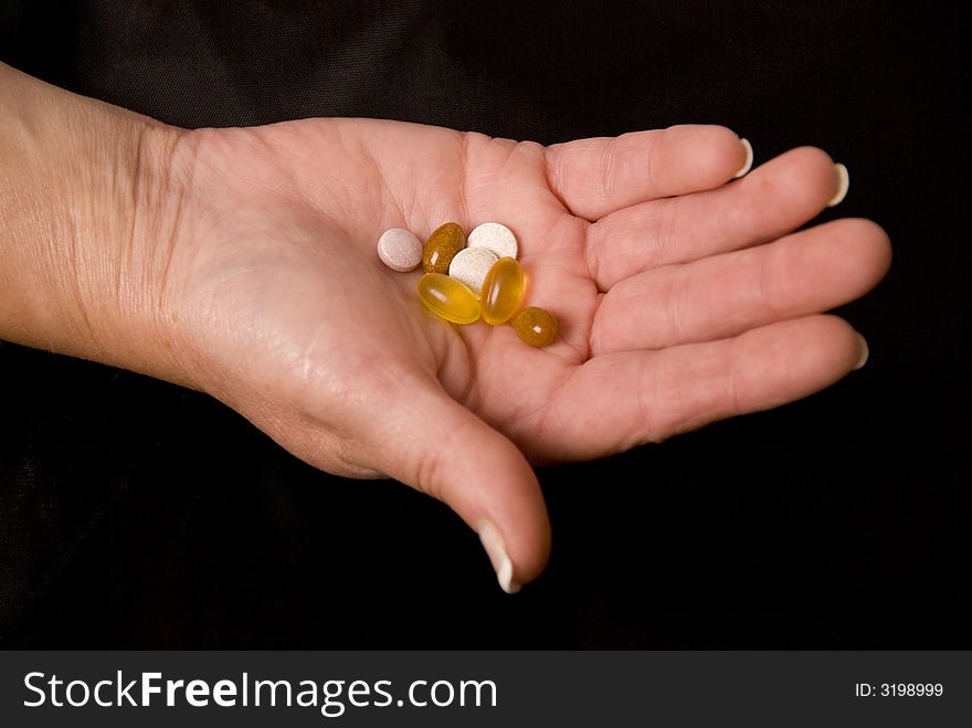 Hand holding pills and tablets on black background. Hand holding pills and tablets on black background