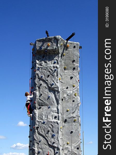 A young blond girl climbs a rock wall. A young blond girl climbs a rock wall.